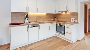 Una cocina moderna con armarios blancos, encimera de madera, horno empotrado y cafetera.