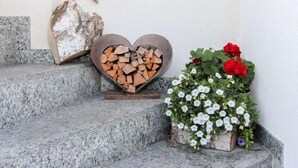 Una escalera de piedra con un portavelas en forma de corazón y una jardinera con flores rojas y blancas.