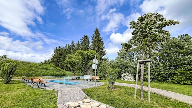A park with a swimming pool, benches, and a stone pathway. - Sonnenmatt App. 12 by Interhome (Höchenschwand)