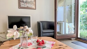 A room with a wooden table, a framed picture on the wall, a black chair, and a sliding glass door leading to an outdoor area. - Sonnenmatt App. 12 by Interhome (Höchenschwand)
