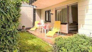 A balcony with two yellow striped lounge chairs, a small table, and a potted plant. - Sonnenmatt App. 12 by Interhome (Höchenschwand)