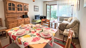 A dining area with a table set for four, a television, a sofa, and a cabinet. - Sonnenmatt App. 12 by Interhome (Höchenschwand)