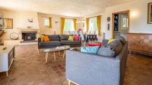 A spacious living room with a fireplace, a dining area, and a kitchen. - La Mesnière by Interhome (Vence)
