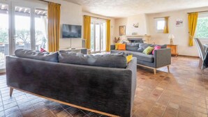 A living room with a sofa, TV, and a fireplace. - La Mesnière by Interhome (Vence)