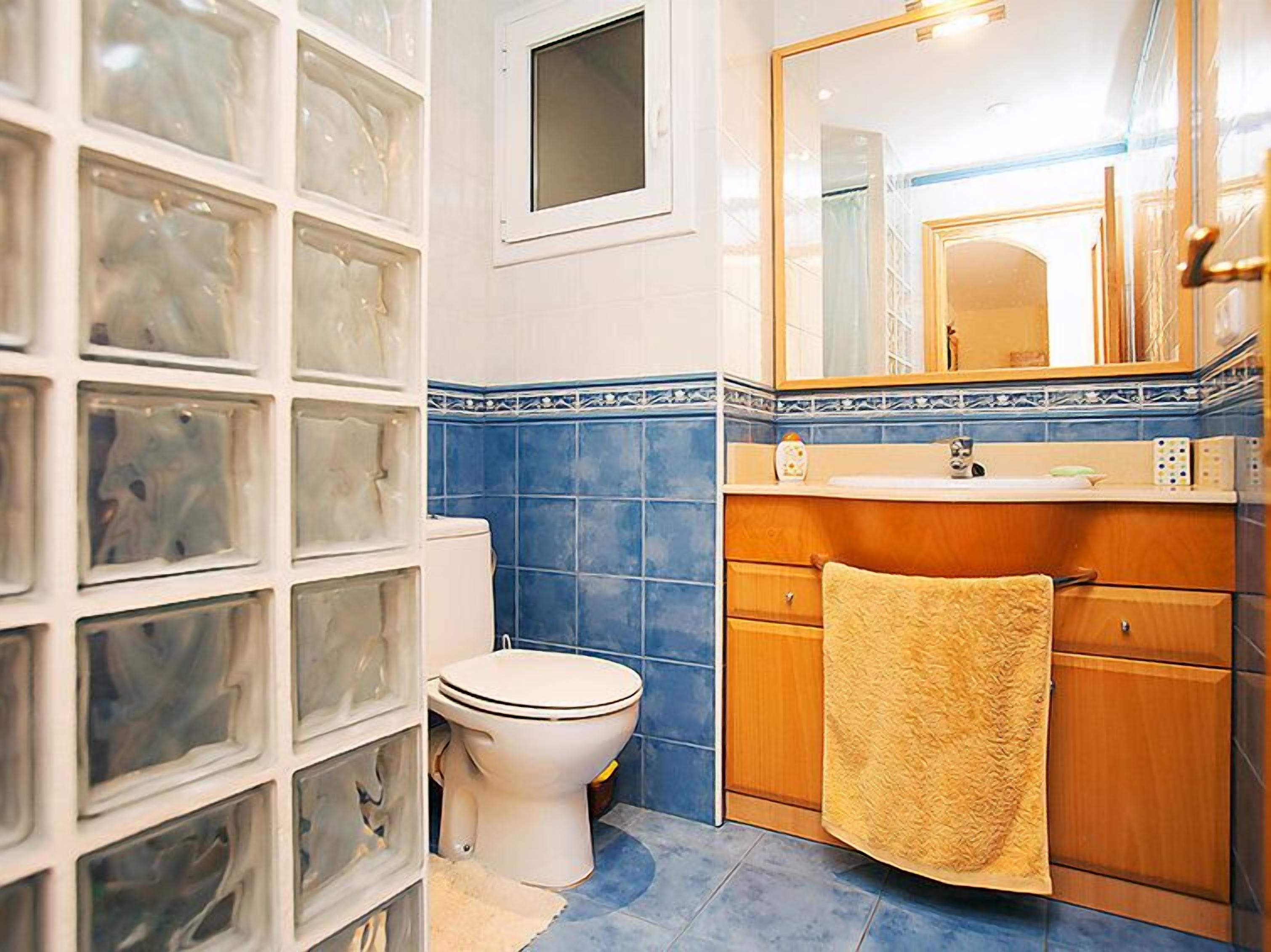 A bathroom with a toilet, sink, and mirror.