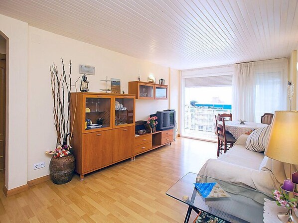 A living room with a wooden cabinet, a glass coffee table, and a view of the outside.