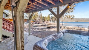 Ein Whirlpool unter einer Holzpergola mit Seeblick und einem Garten mit Grillplatz.