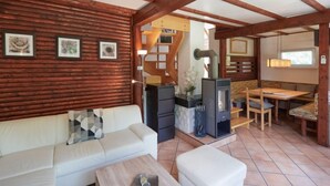 Un acogedor interior de cabaña con techo de madera, un sofá, una mesa de comedor y una chimenea.