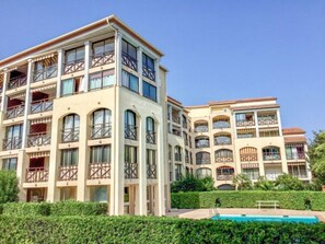 A multi-story hotel with balconies, a swimming pool, and lush greenery.