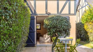 Een terras met een tafel, stoelen, een kleine boom en een ingang van een gebouw.