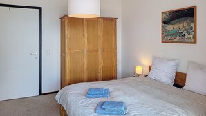 Un dormitorio con cama, armario, un cuadro en la pared y lámpara.
