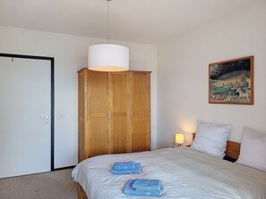 Un dormitorio con cama, armario, un cuadro en la pared y lámpara.