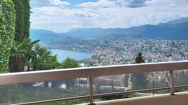 Un balcón con vista a un paisaje urbano y montañas.