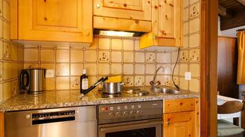 Een koelkast, een oven, een vaatwasser, kookgerei, borden en bestek