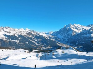 Ein mit Schnee bedeckter Ski-Hang mit Sessellift und einem Skifahrer.