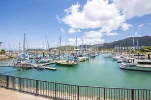 Un port de plaisance avec des bateaux amarrés, un ciel dégagé et des montagnes en arrière-plan.
