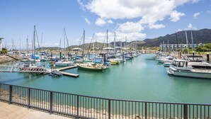 Un port de plaisance avec des bateaux amarrés, un ciel dégagé et des montagnes en arrière-plan.