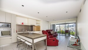 Une cuisine moderne avec un îlot central, des tabourets de bar, un canapé en cuir rouge et une table basse en verre.