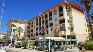 Et hotel med flere etager, altaner, udendørs restaurantpladser og palmer.
