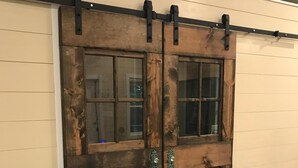 Una puerta corredera tipo granero, con una guía metálica y dos pomos.