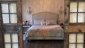 Un dormitorio con cama, puertas correderas de madera y un papel tapiz estampado.