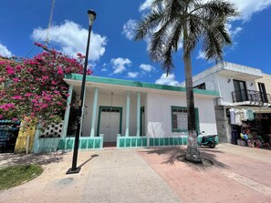 Un edificio con fachada blanca, detalles verdes y un balcón.