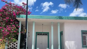 Un edificio con fachada blanca, detalles en verde y una puerta blanca.
