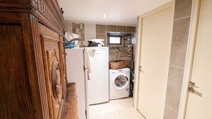A compact kitchen with a washing machine, a refrigerator, and a microwave.