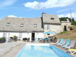 Un edificio de piedra con piscina, mobiliario exterior y cielo despejado.