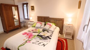 A bedroom with a bed, bedside tables, a wooden headboard, a mirror, and a door. - Homerez - Villa in Vieillevie + private pool (Vieillevie)