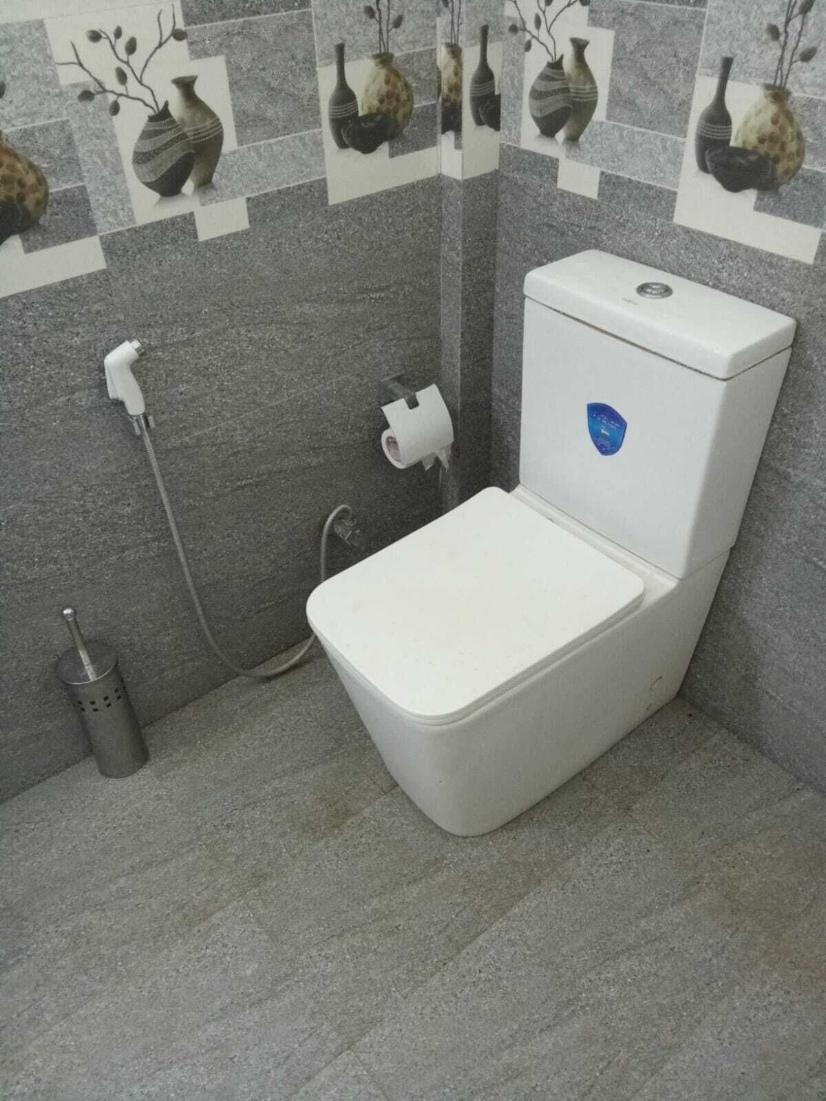A bathroom with a white toilet, a hand dryer, and a paper towel dispenser.