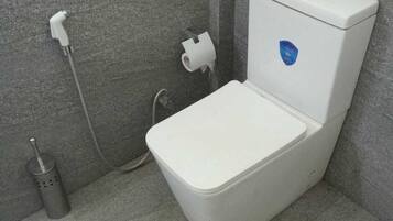 A bathroom with a white toilet, a hand dryer, and a paper towel dispenser.