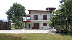 A two-story house with a balcony, a gated entrance, and a paved driveway. - White House Holiday Home (Maspotha)