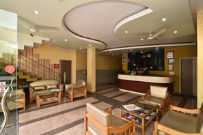 A hotel lobby with a reception desk, seating area, and a staircase. - Hotel Galaxy (Dehradun)