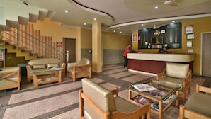 A lobby with a reception desk, seating area, and a staircase. - Hotel Galaxy (Dehradun)