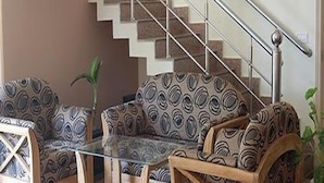 A staircase with a metal railing, a patterned sofa, and a glass coffee table in a living area. - Hotel Galaxy (Dehradun)