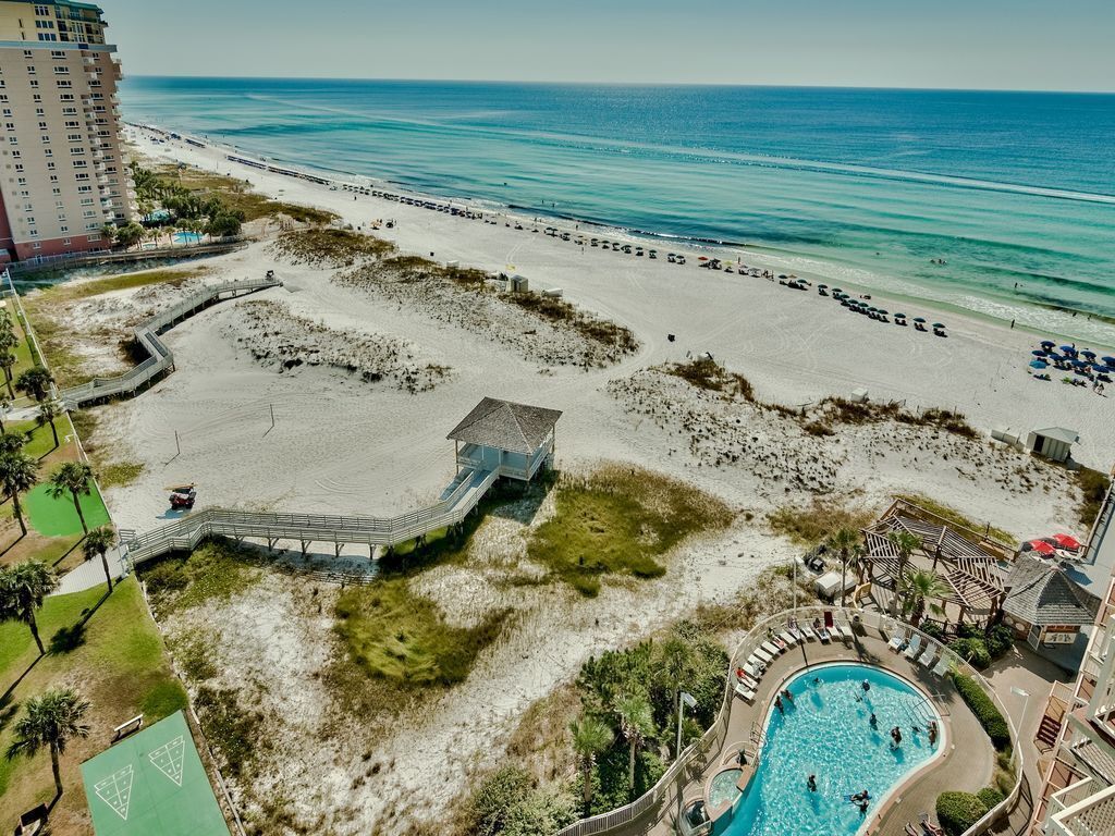 A beach resort with a swimming pool, beach access, and a view of the ocean.