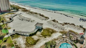 A beach resort with a swimming pool, beach access, and a view of the ocean.