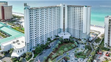 A high-rise hotel with a central courtyard, a pool, and a beach view.