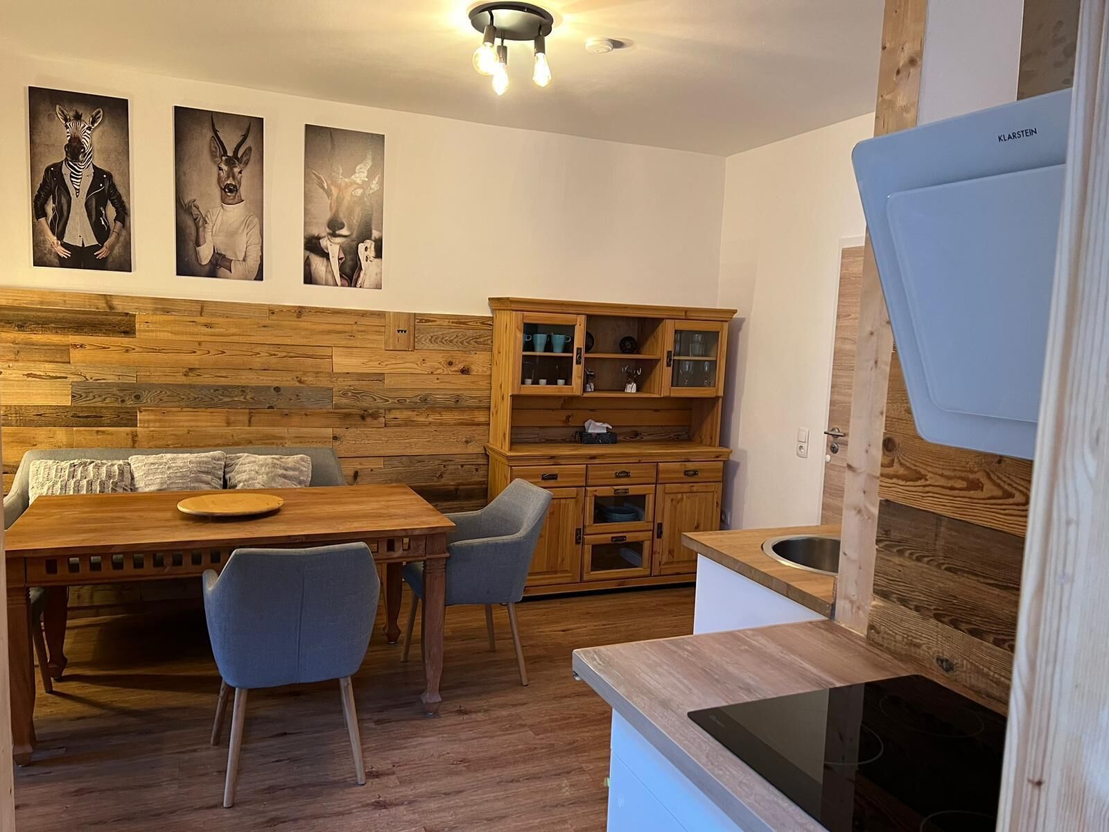 Eine moderne Küche mit Holzschränken, einem Essbereich mit Holztisch und Stühlen sowie einem eingebauten Herd.