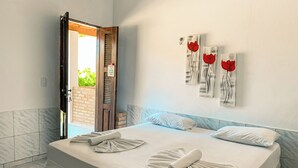 A neatly made bed with towels, a marble-tiled floor, and a wall with abstract art. - Pousada La Goduria (Aracati)