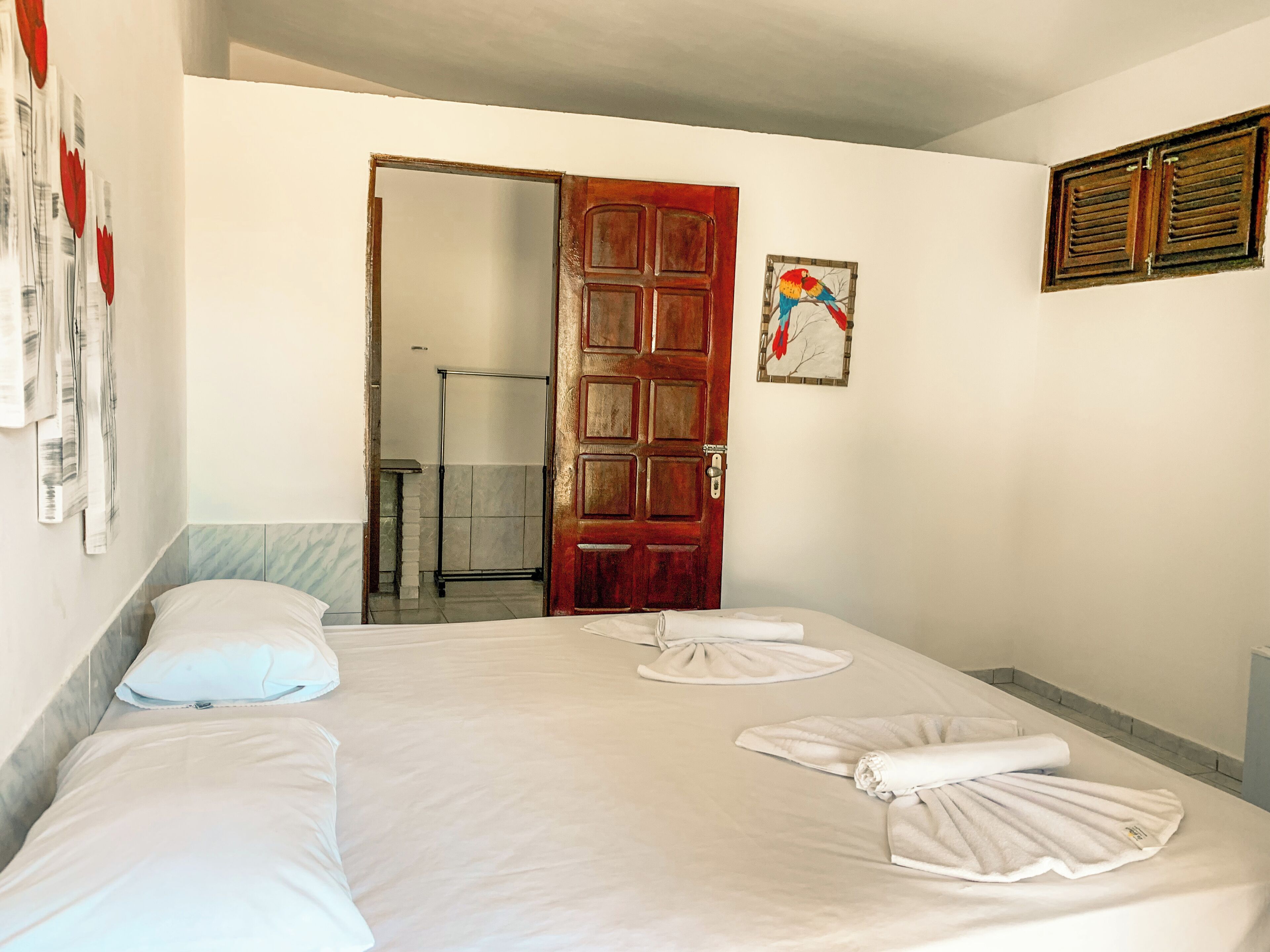 Habitación de hotel con cama, dos almohadas, una toalla, una puerta de madera y zona de ducha.