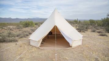 A dome-shaped tent in a desert landscape with mountains in the background.