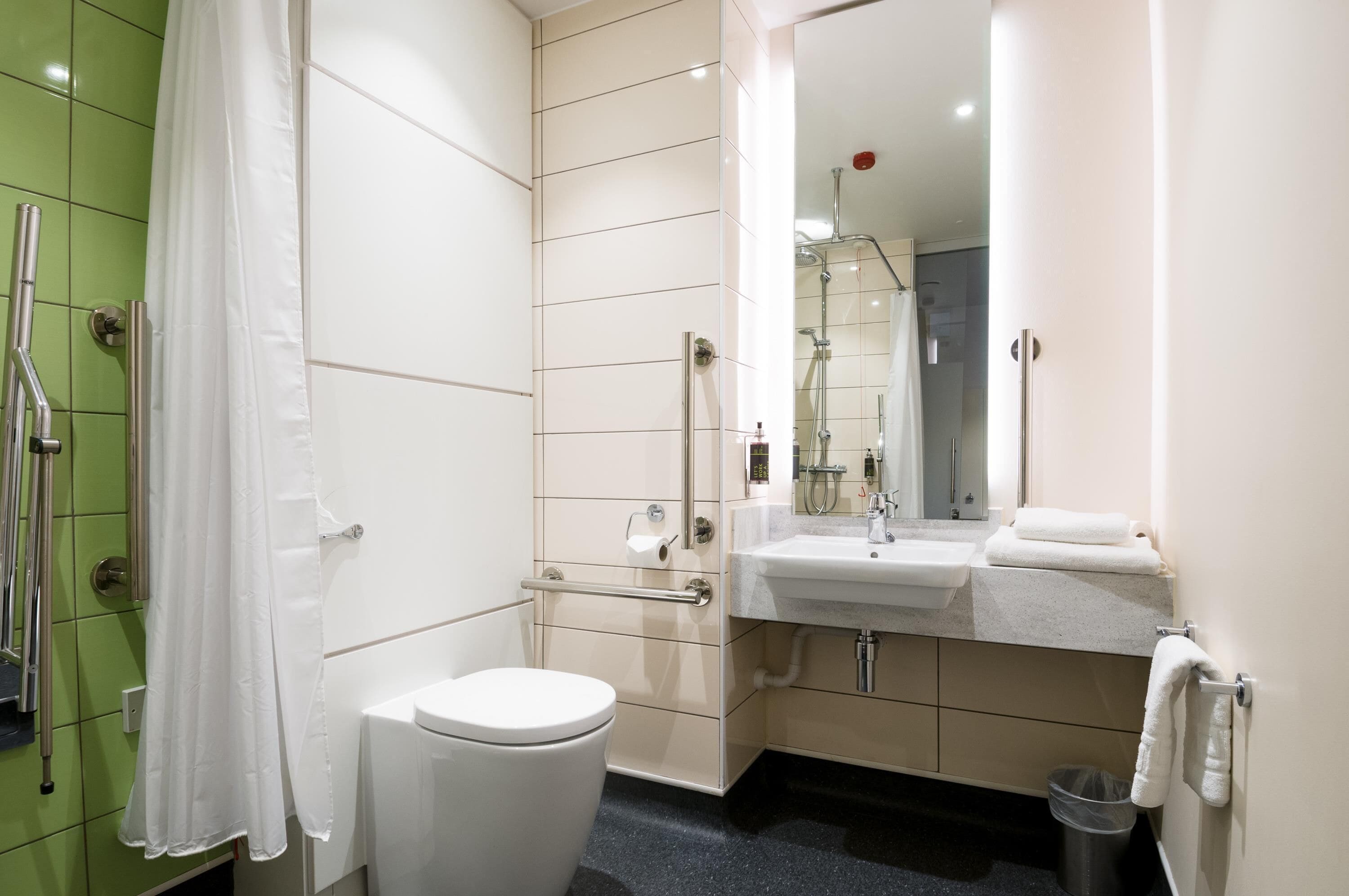 Un baño moderno con ducha, inodoro, lavabo y espejo.