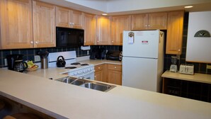 A kitchen with wooden cabinets, a stove, a microwave, a refrigerator, and a toaster.