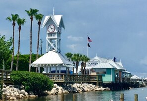 A coastal building with a clock tower, a flag, and a dock extending into the water.