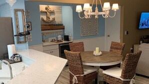 Una cocina moderna con una isla central, sillas de comedor, una lámpara de araña y un reloj en la pared.