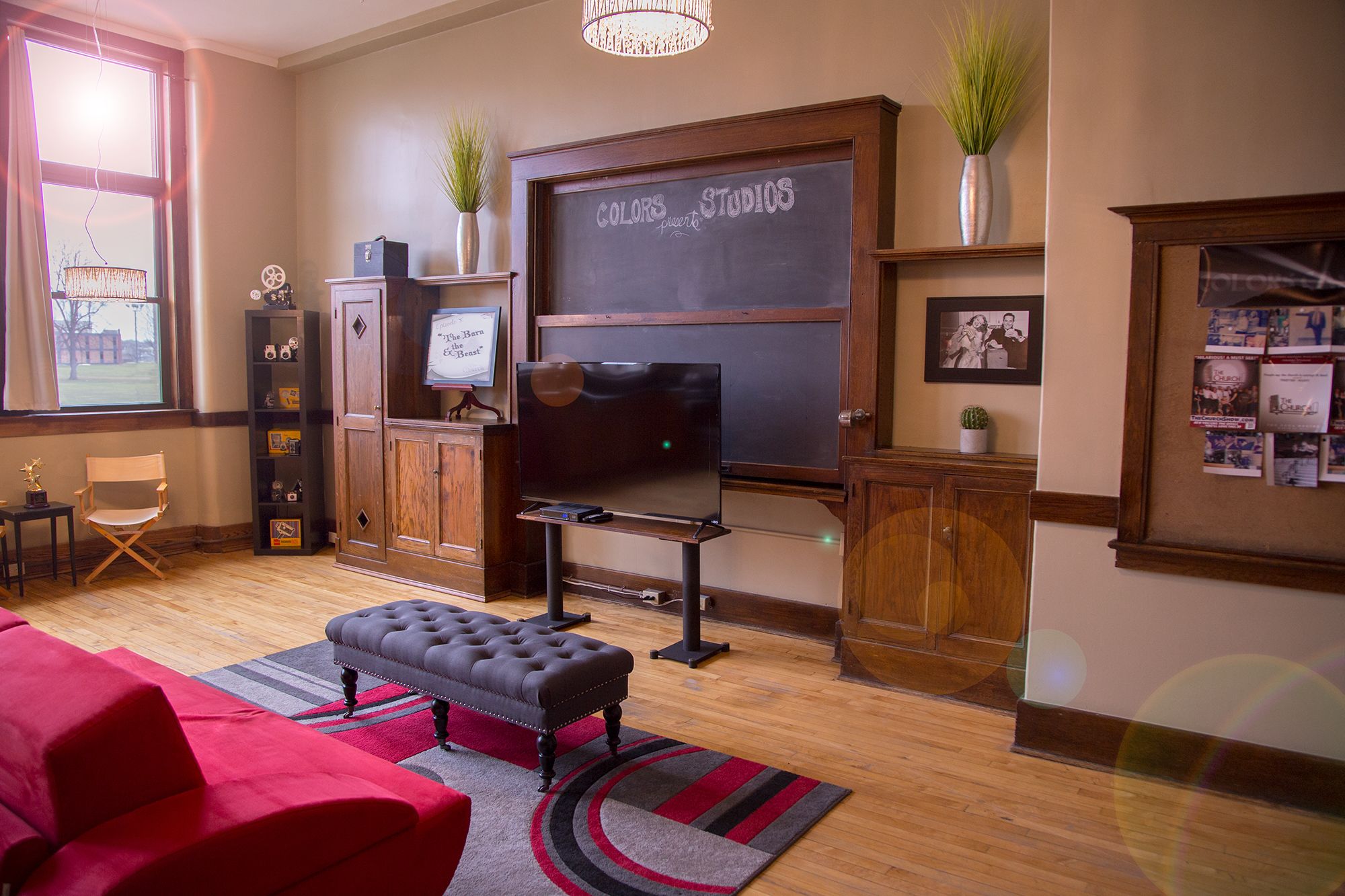 A cozy living room with a television, a red sofa, a wooden cabinet, and a chalkboard wall.