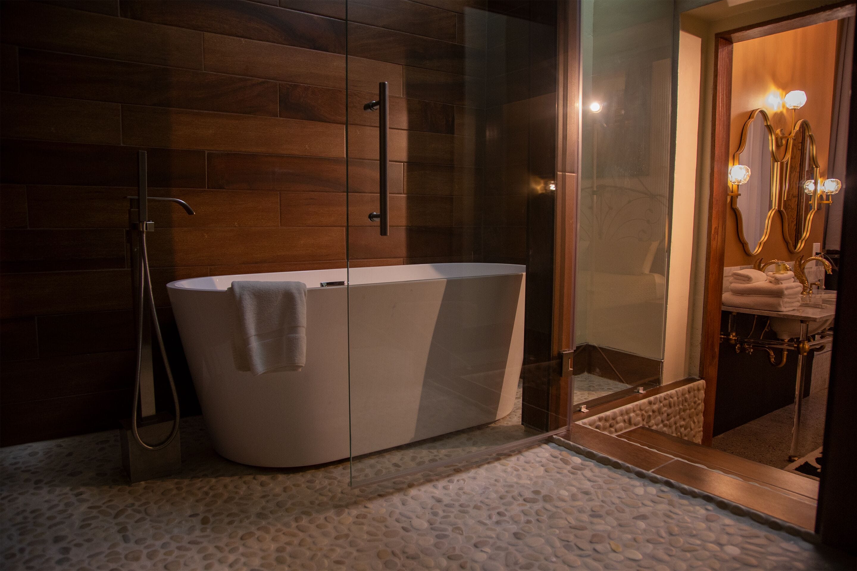 A modern bathroom with a freestanding bathtub, a glass shower enclosure, and a vanity with a mirror and lights.