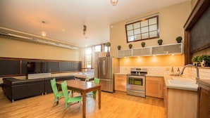 A modern kitchen with a dining area, built-in appliances, and a large window. - School 31 Lofts at Colors Studios (Rochester)